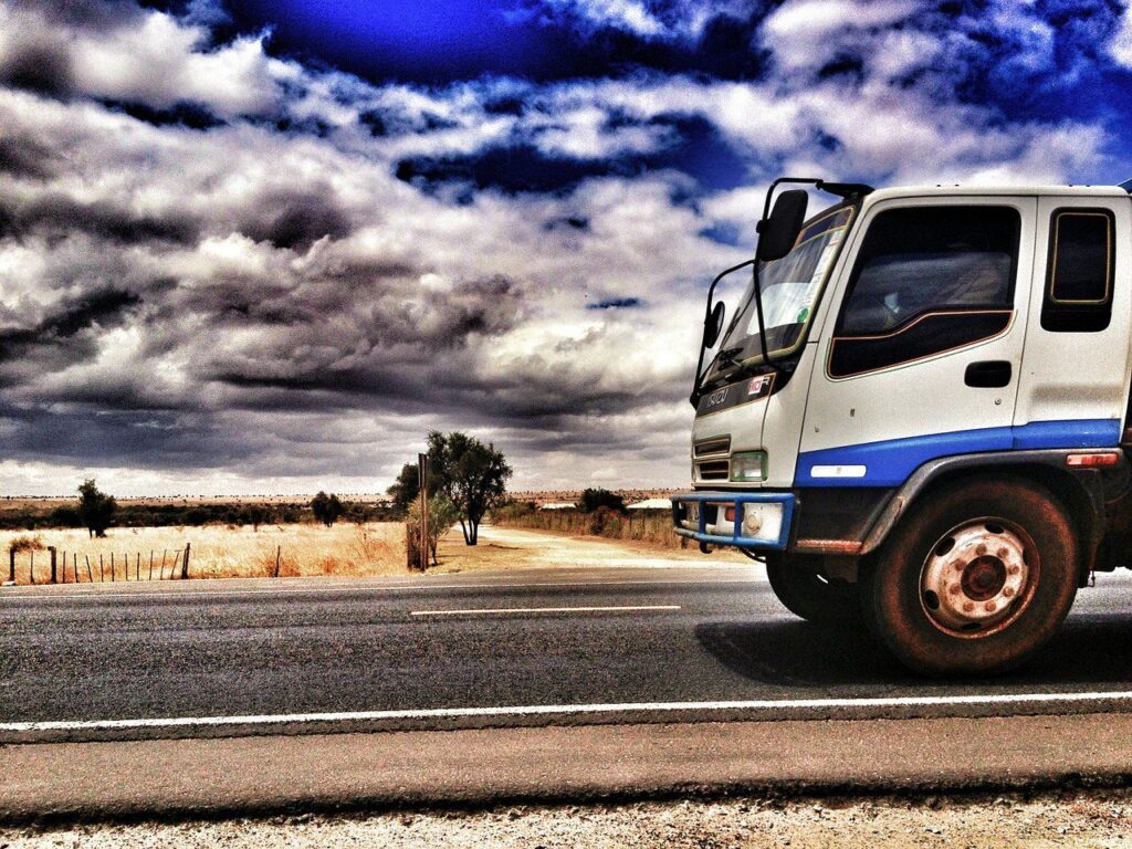 Front cab of truck riding on highway, sand, dirt, trees in background