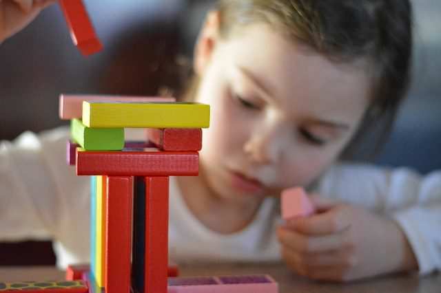 young child building with colorful wooden blocks