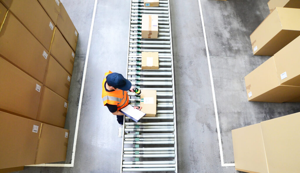 Workers in a mail order company scan packages for shipping // Arbeiter in einem Versandhandel scannt Pakete für den Versand ein