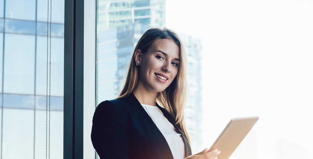 Smiling businesswoman using tablet in modern office building