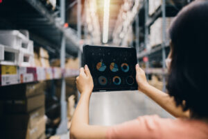 A woman holding up a tablet in a warehouse using AI in logistics and transportation