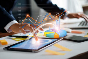 Business growth charts popping out of a tablet and laptop as a result of AI consulting for business transformation.