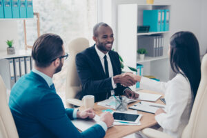 A black business man shaking the hand of a woman from an AI consulting firm for private equity groups.