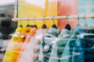 Different colored jackets on a clothing rack.