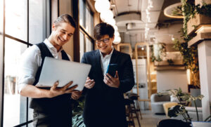 Two business leaders looking joyfully at an ai product a firm made for them after they read the ai consulting practical guide for small business leaders.