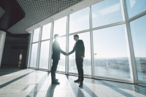 A young CEO shaking hands with a leader of an ai consulting firm. They are making a deal because AI is essential for modern enterprises.