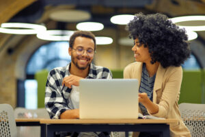 Two young happy multiracial tech workers collaborating on a generative AI consulting project