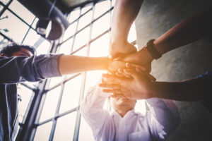 Business team with hands in the middle of a circle representing teamwork.