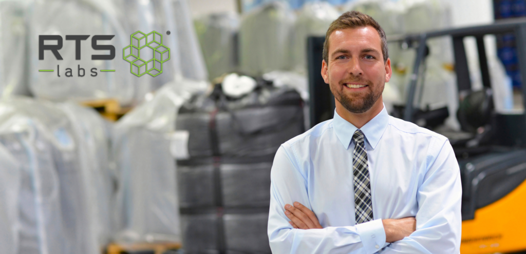 A happy business man in a tie crossing his arms in a logistics warehouse because of demand forecasting with AI