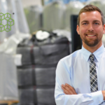 A happy business man in a tie crossing his arms in a logistics warehouse because of demand forecasting with AI