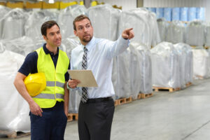 A businessman pointing out something great to a logistics worker. Their efficiency is through the roof thanks to demand forecasting with AI.