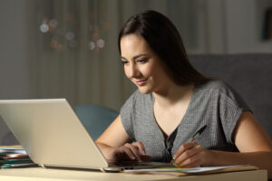 A woman guiding large language models on her computer smiling