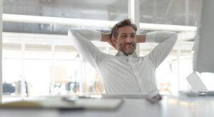 Man relaxing at computer because of AI office management automation.