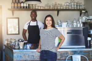 Man and woman in coffee shop smiling and using ai oin the hospitality industry.