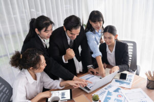 An office team looking at a computer and celebrating their efficiency thanks to emergence orchestrator.