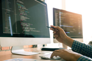 Developer working on a computer pointing to it with a pen.