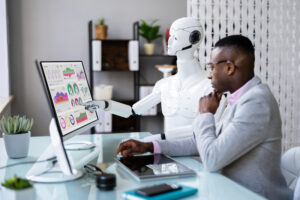 A black man with a robot working together on a computer.