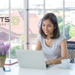 Asian woman on a computer happy to use the assistance of an AI agent in the agentic age.