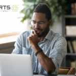 An African-American man smiling at his computer thinking about a future with AI as a moral partner