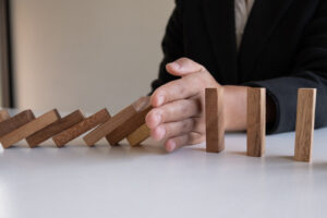 A man blocking domino blocks representing the overcoming of challenges in AI deployment.