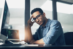 A man working hard on his computer at a tech company. Latino