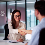 A woman shaking hands with a man hiring AI consultants for her company.