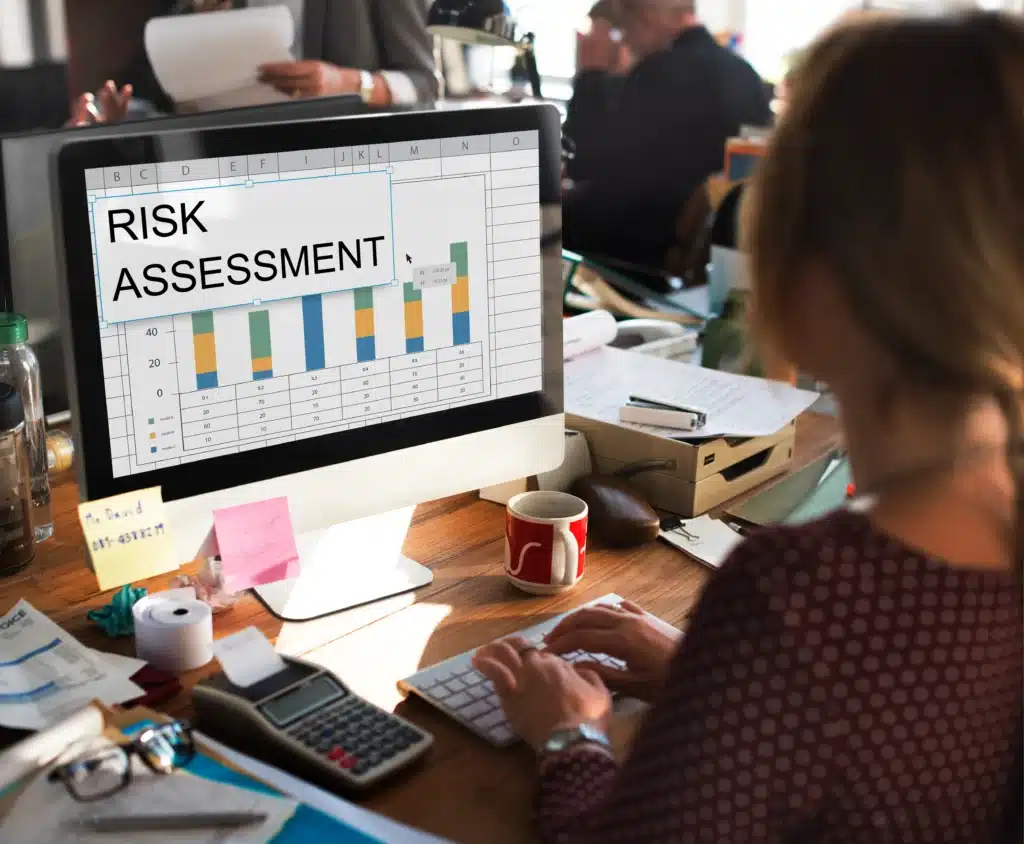 A professional at a desk analyzing a risk assessment chart on a computer screen, representing the use of fraud analytics for detecting and preventing fraud.