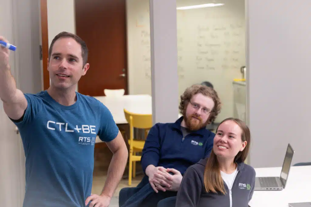 RTS Labs team members mapping out a workflow at a whiteboard